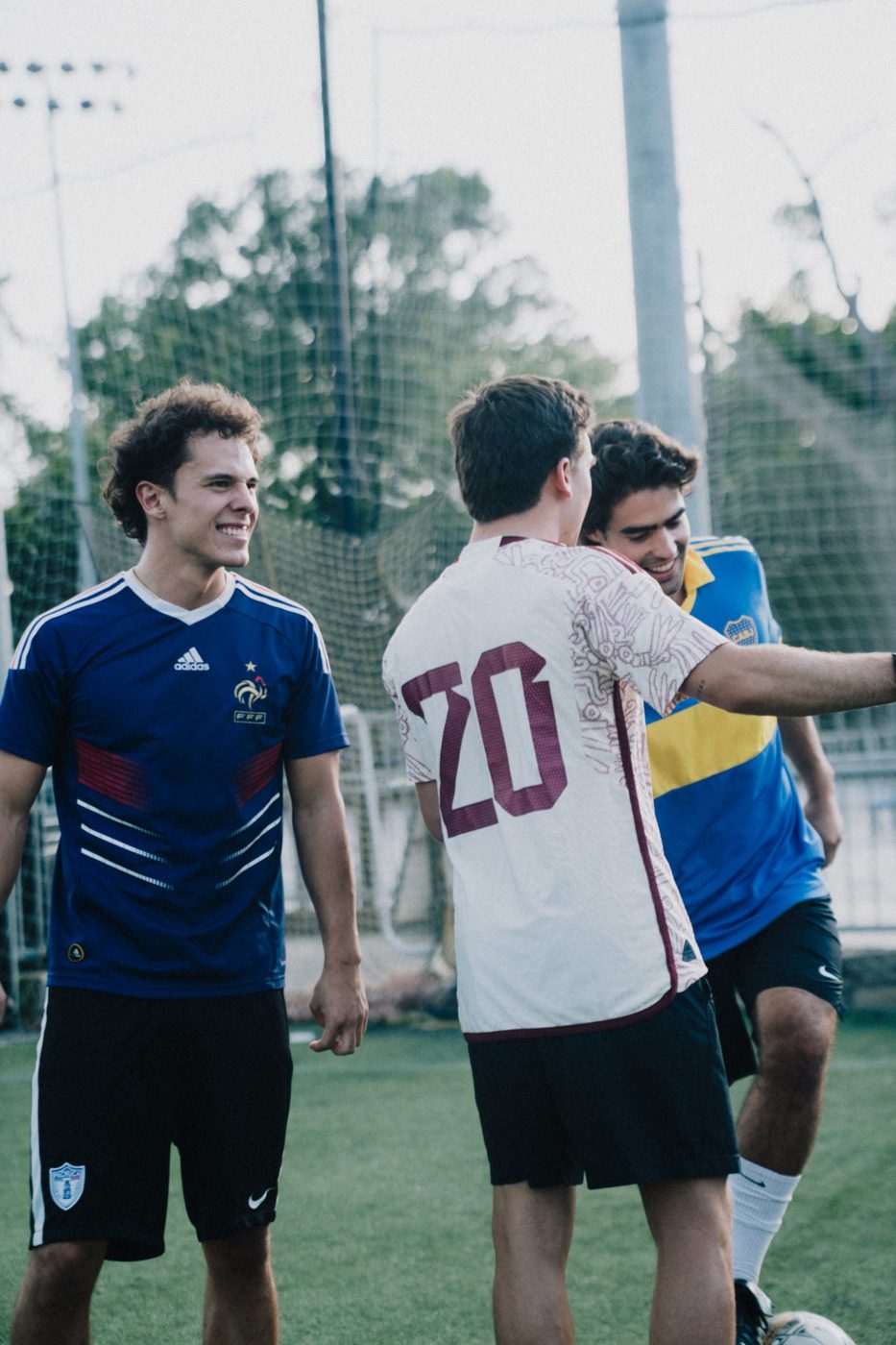 Three adult players laugh and greet each other on the field