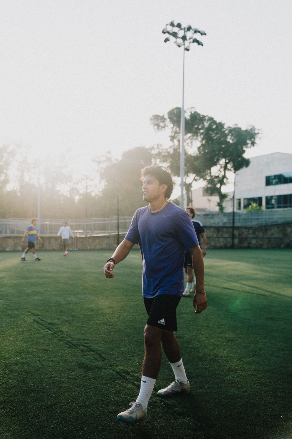 An adult player walks across the field in the evening sun