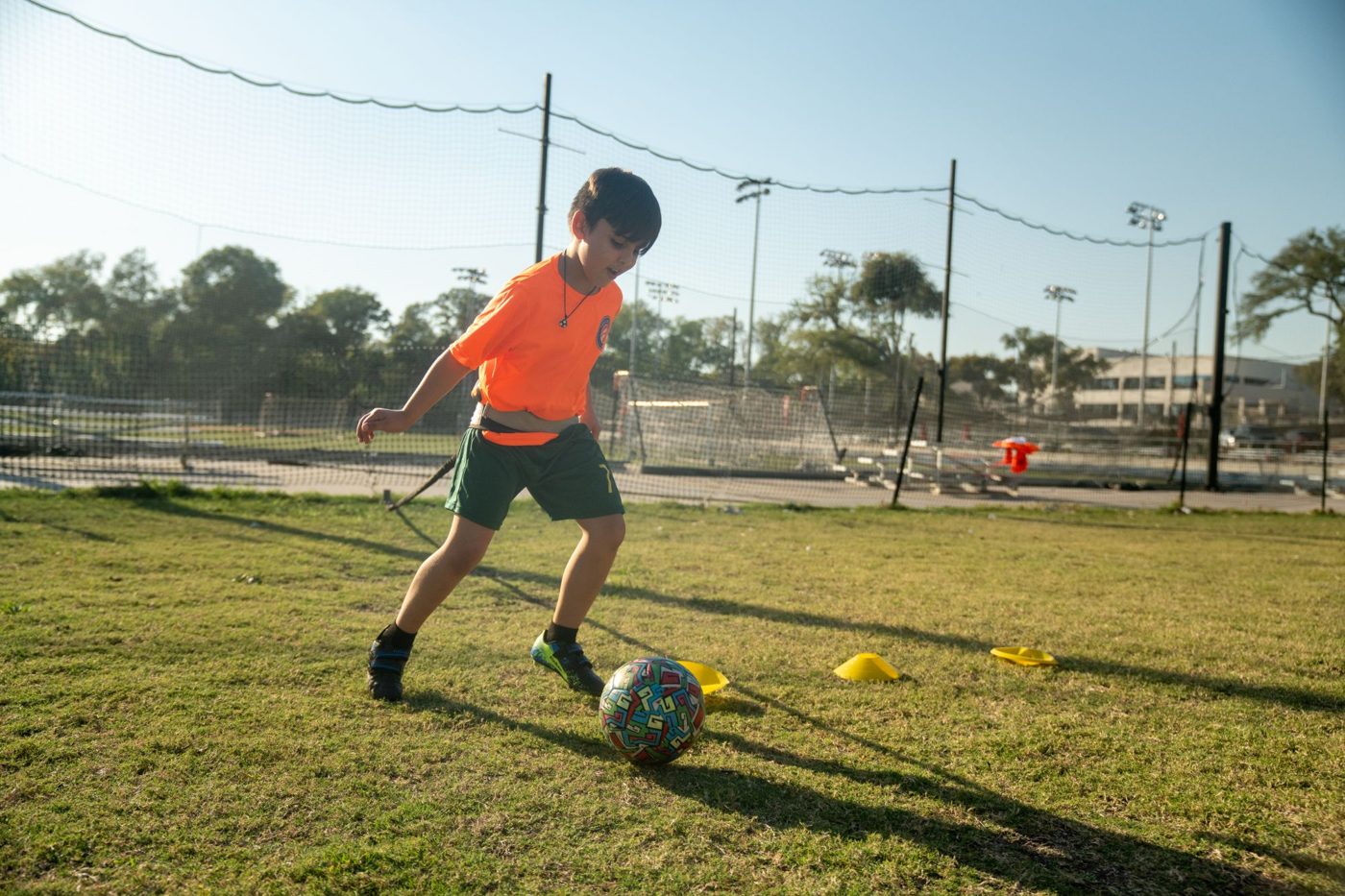 A young player dribbling a ball past cones