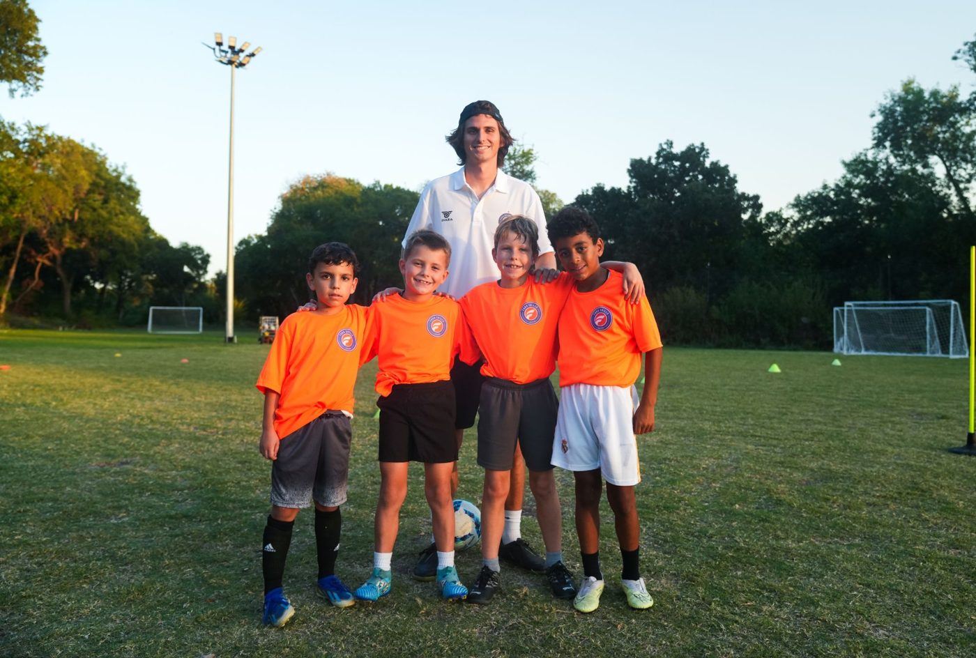 A Foro coach and four young players smiling together on the field