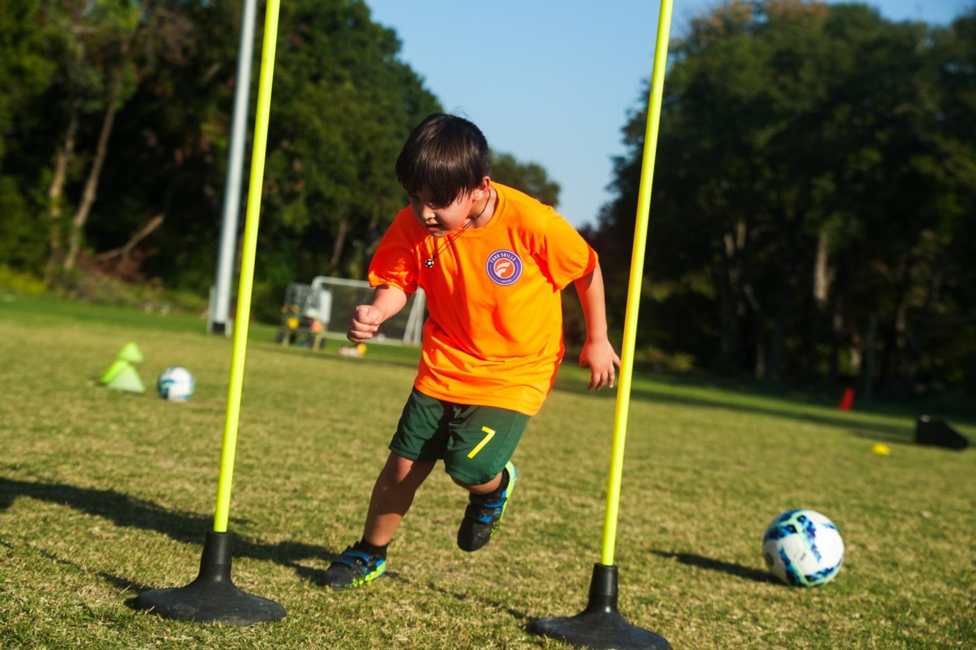 A young player in a Foro Skills shirt running through agility poles