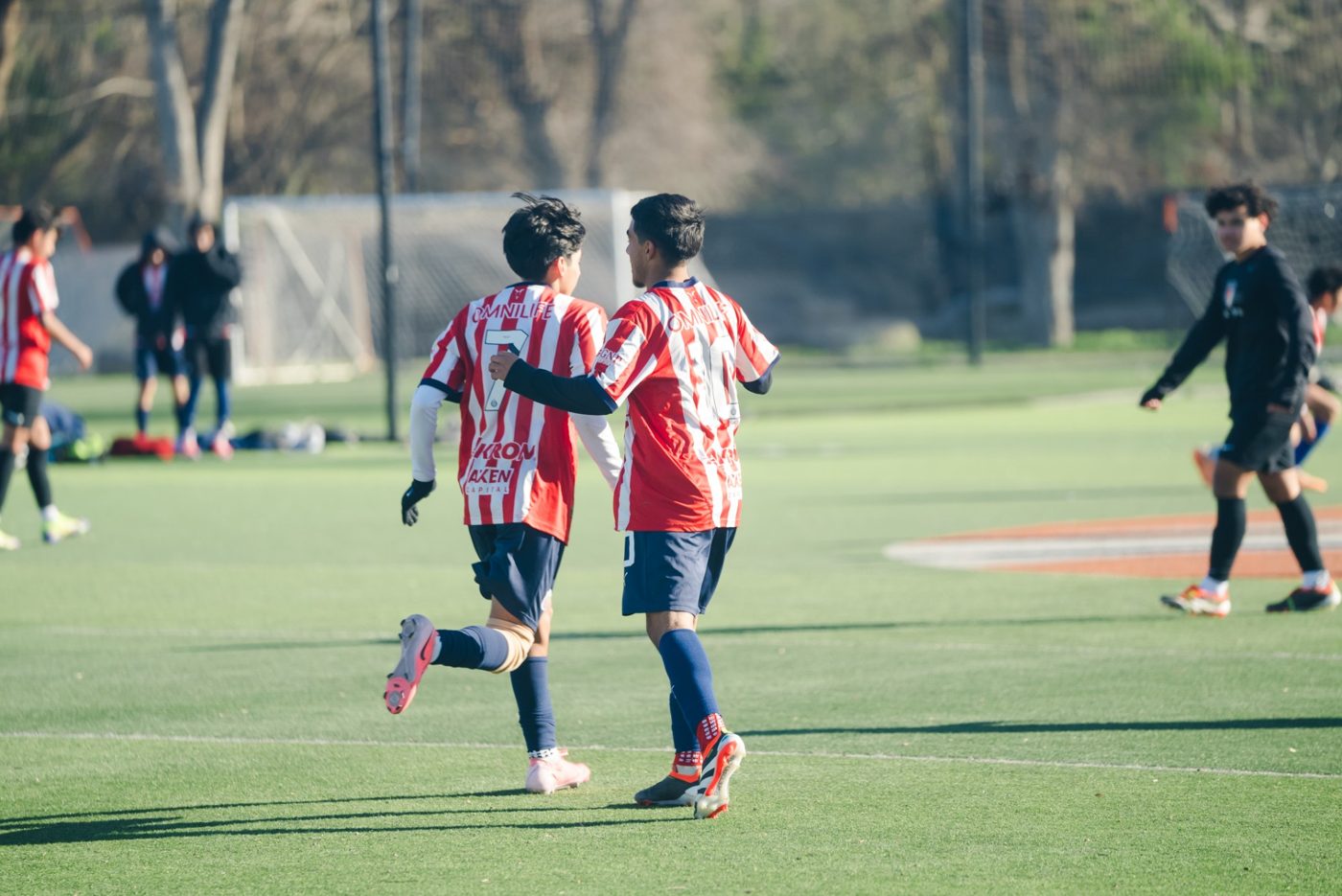 Two players in red and white striped jerseys celebrate during a league match