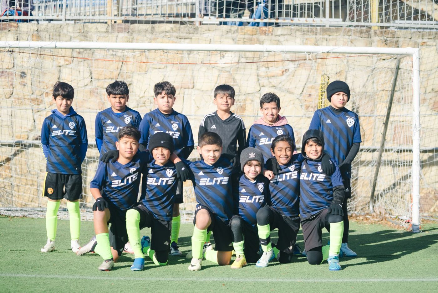 A youth team in blue ELITE jerseys poses in front of the goal
